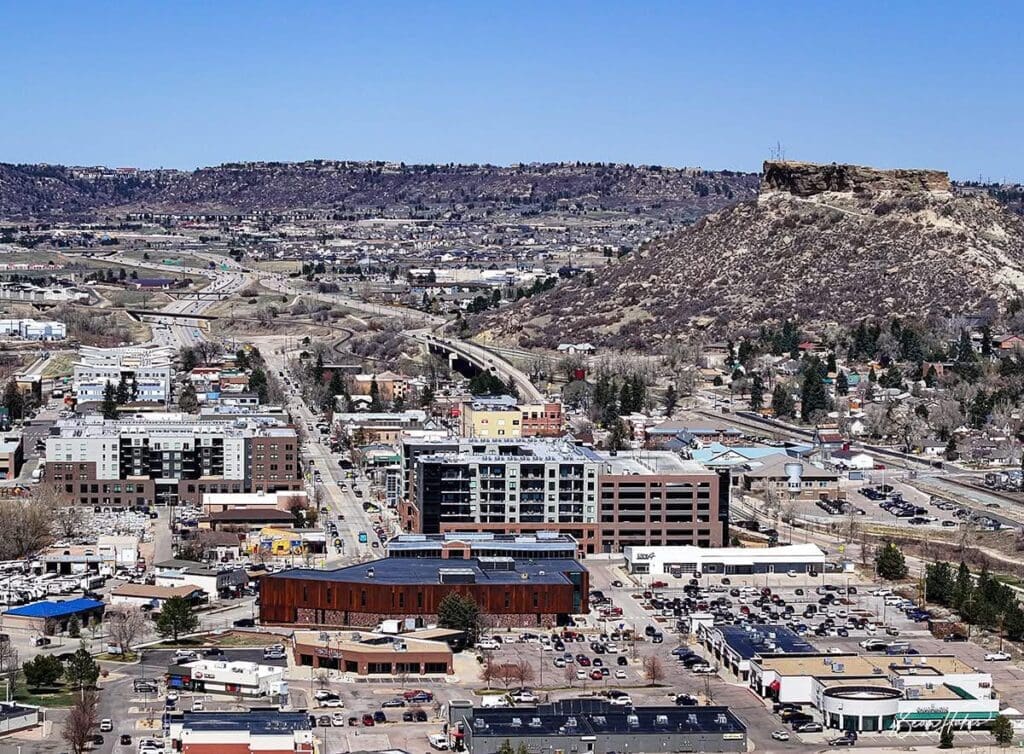 A large crowd gathers near a hill with a historic fort on top.